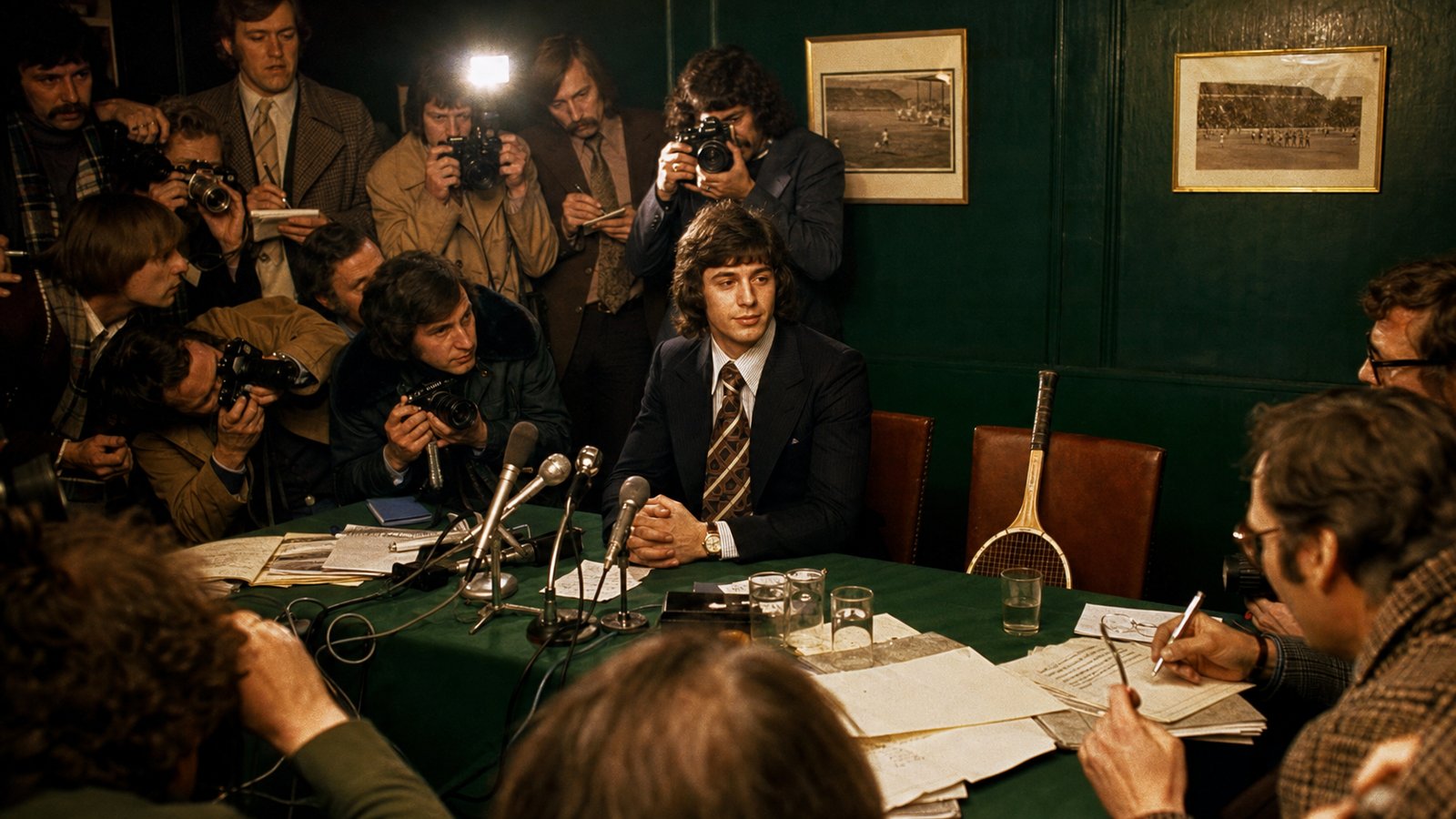 A late-1970s football transfer press room with a suited forward, reporters and an empty chair holding a squash racket, shown with fictional unbranded figures